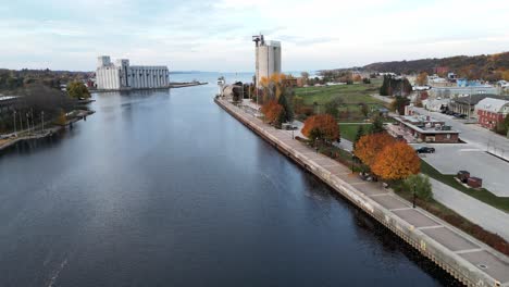 Drone-flying-over-a-river-running-through-a-small-Ontario-town-in-autumn