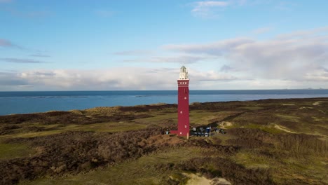 Drone-footage-cirkeling-around-a-big-red-lighthouse-at-the-beach-in-Ouddorp,-The-Netherlands