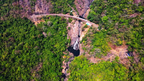 Vista-Aérea-Panorámica-De-Las-Cascadas-Dudhsagar-Con-Puente-Ferroviario-En-El-Parque-Nacional-Mollem,-Sur-De-Goa,-India