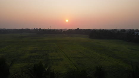 Sonnenuntergang-über-Grünen-Feldern-Und-Fluss-Im-Ländlichen-Indien---Rückzug-Aus-Der-Luft