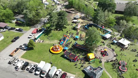 Hyperlapse-aerial-orbit-of-Dogwood-Festival-kids-park-bounce-castle-and-attractions,-Siloam-Springs,-Arkansas