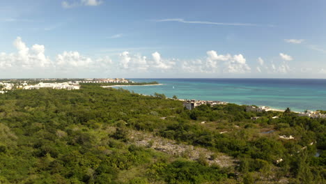 Wooded-coastline-with-white-sand-beach-along-tropical-ocean-bay