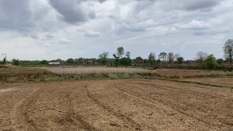 Wide-shot-of-a-recently-ploughed-farm-in-a-village-in-Jharkhand,-India-in-a-cloudy-weather
