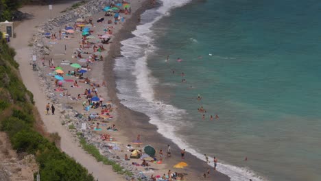 People-relaxing-on-Italian-beach-seen-from-high-angle-point-of-view,-Liguria-in-Italy
