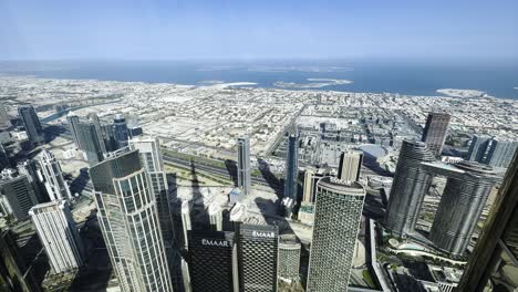 Slow-motion-shot-looking-over-downtown-and-out-to-sea-from-the-Burj-Khalifa,-Dubai