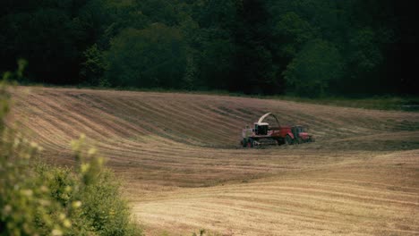 A-tractor-harvests-crops-in-a-French-field-while-birds-of-prey-circle-overhead,-seeking-their-next-meal
