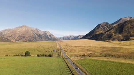 Straight-road-in-between-fields-and-majestic-mountains