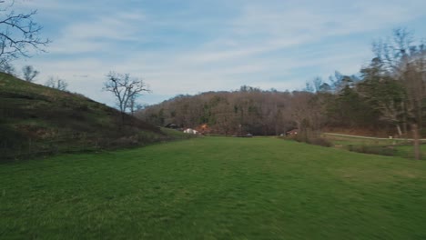 FPV-drone-shot-of-flying-through-green-field-with-power-lines-and-up-steep-green-hill-side-in-early-spring-and-winter