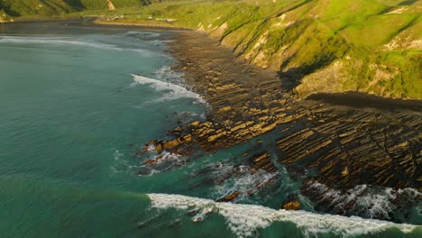 Ancient-volcanic-fossil-rocks-on-shore-of-New-Zealand-at-sunset,-aerial