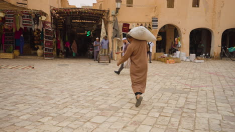 Mann,-Der-Waren-Auf-Dem-Markt-In-Der-Altstadt-Von-Ghardaia,-Algerien,-Trägt