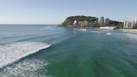 Surfers-On-Waves-Rolling-At-Burleigh-Heads-Beach-In-Queensland,-Australia---aerial-drone-shot