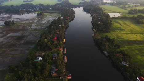 Aerial-View-Of-Calm-River-Surrounded-With-Vegetation-And-Agricultural-Fields-In-India---drone-shot