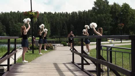 Cheerleader-Schütteln-Pompons,-Während-Der-Triathlet-In-Zeitlupe-über-Die-Brücke-Rennt