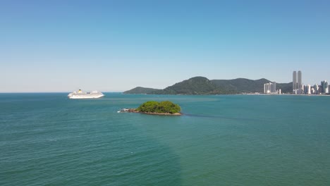 Drone-shot-of-an-island-near-a-city-with-a-cruise-ship-approaching