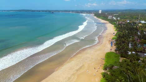 Vista-Aérea-De-Una-Larga-Playa-De-Surfistas-En-Weligama,-Sri-Lanka-En-Un-Hermoso-Día-Soleado-De-Verano