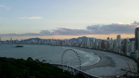 Aerial-view-of-the-city-of-Balneario-Camboriu-at-sunset-with-the-Ferris-wheel-and-tall-buildings