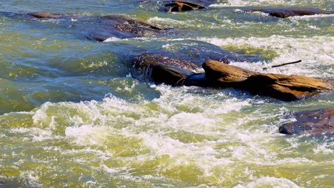 Foamy-white-water-river-rapids-flowing-over-rocks-in-bright-sunlight