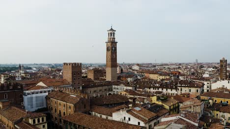 Drone-shot-of-a-looming-brick-tower-standing-over-Verona,-Italy