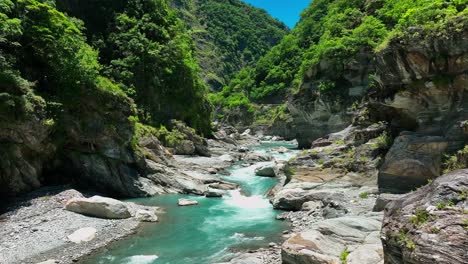 Vuelo-Lento-De-Drones-Sobre-Un-Hermoso-Arroyo-Que-Fluye-Por-Verdes-Colinas-En-El-Parque-Nacional-Durante-El-Día-Soleado---Parque-Nacional-Taroko,-Taiwán