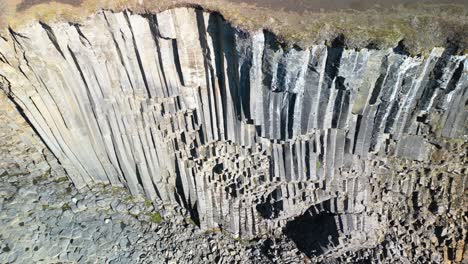 Aerial-drone-pan-shot-from-left-to-right-over-rocky-columns-along-Studlagil-Canyon-with-the-Jokulsa-A-Bru-river-in-east-Iceland,-Europe-at-daytime