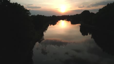 Die-Kamera-Senkt-Sich-über-Das-Flussbett,-Wo-Sich-Bei-Sonnenuntergang-Bunte-Wolken-Spiegeln
