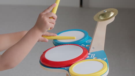 Young-girl-playing-music-on-toy-drum-set