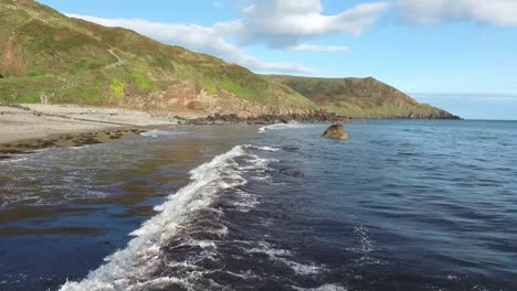 Luftaufnahme-Der-Wellen,-Die-Sich-Am-Felsigen-Strand-Mit-Klippen-Im-Hintergrund-Bei-Porth-Ysgo-Auf-Der-Halbinsel-Llyn-In-Wales-Brechen