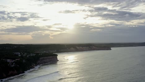 Dolly-in-aerial-drone-wide-landscape-shot-of-the-stunning-tropical-Northeastern-Brazil-coastline-from-Pipa,-Rio-Grande-do-Norte-with-large-clay-cliffs-during-a-warm-sunny-overcast-evening