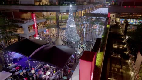 Aerial-flyover-shopping-center-with-decorated-christmas-tree-at-night-during-rainy-day---Taipei-City,-Taiwan