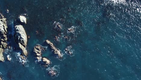 Birdseye-view-of-flying-over-some-rocks-in-shallow-water