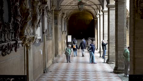 Turistas-Caminando-Bajo-El-Pórtico-Del-Palacio-Dell&#39;Archiginnasio-En-Bolonia