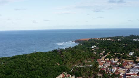 Right-trucking-wide-aerial-drone-shot-of-the-beautiful-tropical-Northeastern-Brazil-coastline-and-the-famous-tourist-town-of-Pipa-in-Rio-Grande-do-Norte-covered-in-exotic-green-foliage