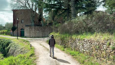 Woman-walking-outside-old-rustic-Italian-cottage-in-Tuscany-countryside