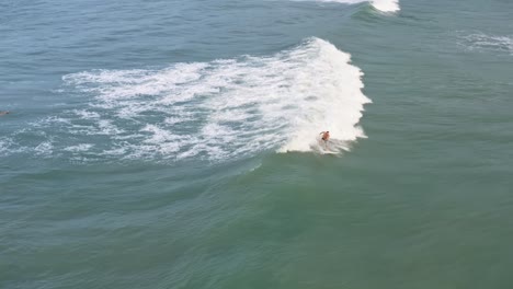 Luftdrohnenaufnahme,-Die-Einem-Surfer-Aus-Einer-Großen-Gruppe-Folgt,-Der-An-Einem-Sommertag-Am-Berühmten-Tropischen-Strand-Pipa-In-Rio-Grande-Do-Norte,-Brasilien,-Eine-Kleine-Welle-Fängt