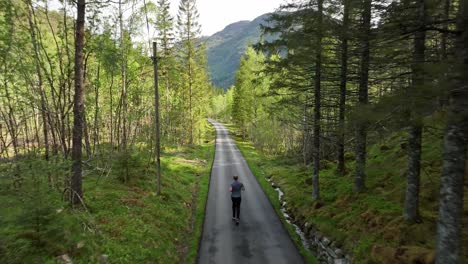 Adult-man-jogs-through-forest-on-paved-road