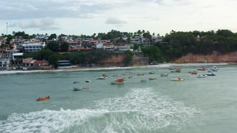 Wunderschöne-Luftdrohnenaufnahme-Einer-Gruppe-Kleiner-Fischerboote,-Die-Bei-Flut-Am-Tropischen-Pipa-Strand-Angedockt-Sind,-Umgeben-Von-Großen-Klippen,-Häusern-Und-Restaurants-In-Rio-Grande-Do-Norte,-Brasilien