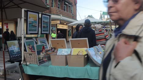 Print-Stall-at-Manly-markets-in-Sydney,-Australia-and-people-walking