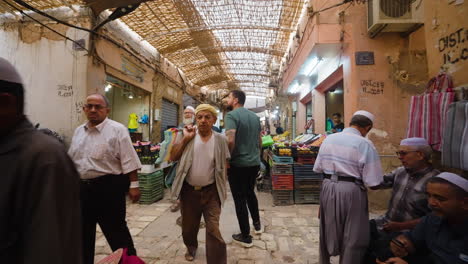 Hombre-Sujetando-Una-Cámara-Caminando-Por-El-Mercado-Local-En-Ghardaia,-Argelia