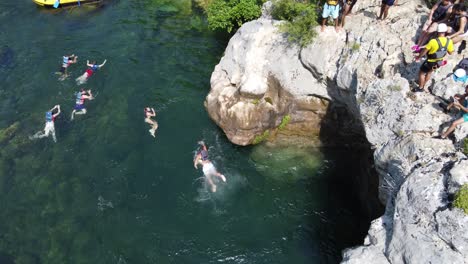 Tourists-cliff-jumping-and-swimming-in-Cetina-river-on-white-water-Rafting-excursion-in-Omis,-Croatia