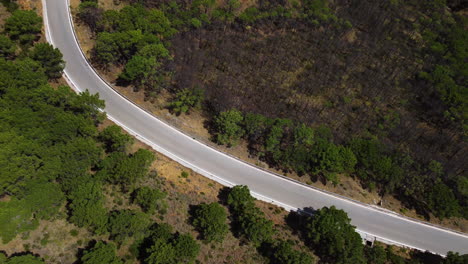 A-drone-tilts-over-a-mountain-pass-road-leading-down-to-Estepona,-Spain