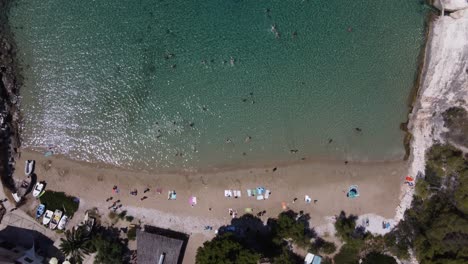 Aerial-bird's-eye-view-of-Porat-Bay-on-Bisevo-Island,-Croatia-with-People-swimming-in-transparent-water-of-the-sandy-Beach