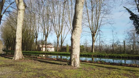 Malerische-Aussicht-Auf-Den-Kanal-Mit-Blick-Durch-Die-Stämme-Großer-Bäume-Im-Frühling