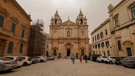 Foto-De-ángulo-Bajo-De-Turistas-Que-Visitan-La-Catedral-De-San-Pablo-En-Mdina,-Malta-En-Una-Tarde-Nublada