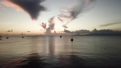 Drone-flying-between-sailboat-during-sunset,-Marie-Galante-Guadeloupe