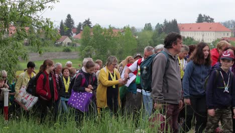 People-on-Csíksomlyó-Pilgrimage-walk-up-hill,-small-village-in-background