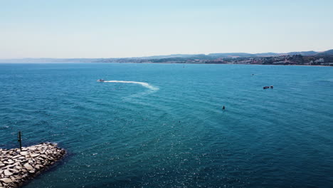 Drone-flies-over-birds,-a-ship-open-waters-near-an-island-on-the-Mediterranean-Sea
