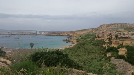 High-angle-shot-over-bay-area-surrounded-by-rocky-highlands-in-eastern-Malta-during-evening-time