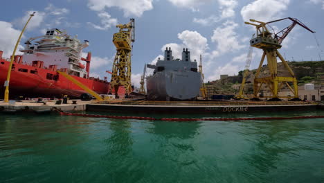 Low-angle-shot-of-container-ships-docked-in-the-port-of-Valletta,-or-Il-Belt,-the-tiny-capital-of-the-Mediterranean-island,-Malta-on-a-cloudy-day