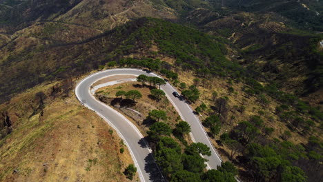 A-drone-pushes-and-tilts-to-an-aerial-of-mountain-road-leading-to-the-shoreline-of-Estepona,-Spain