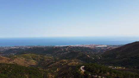 Eine-Drohne-Zeigt-Den-Horizont-Der-Küste-Von-Der-Spitze-Der-Berge-Nach-Estepona,-Spanien